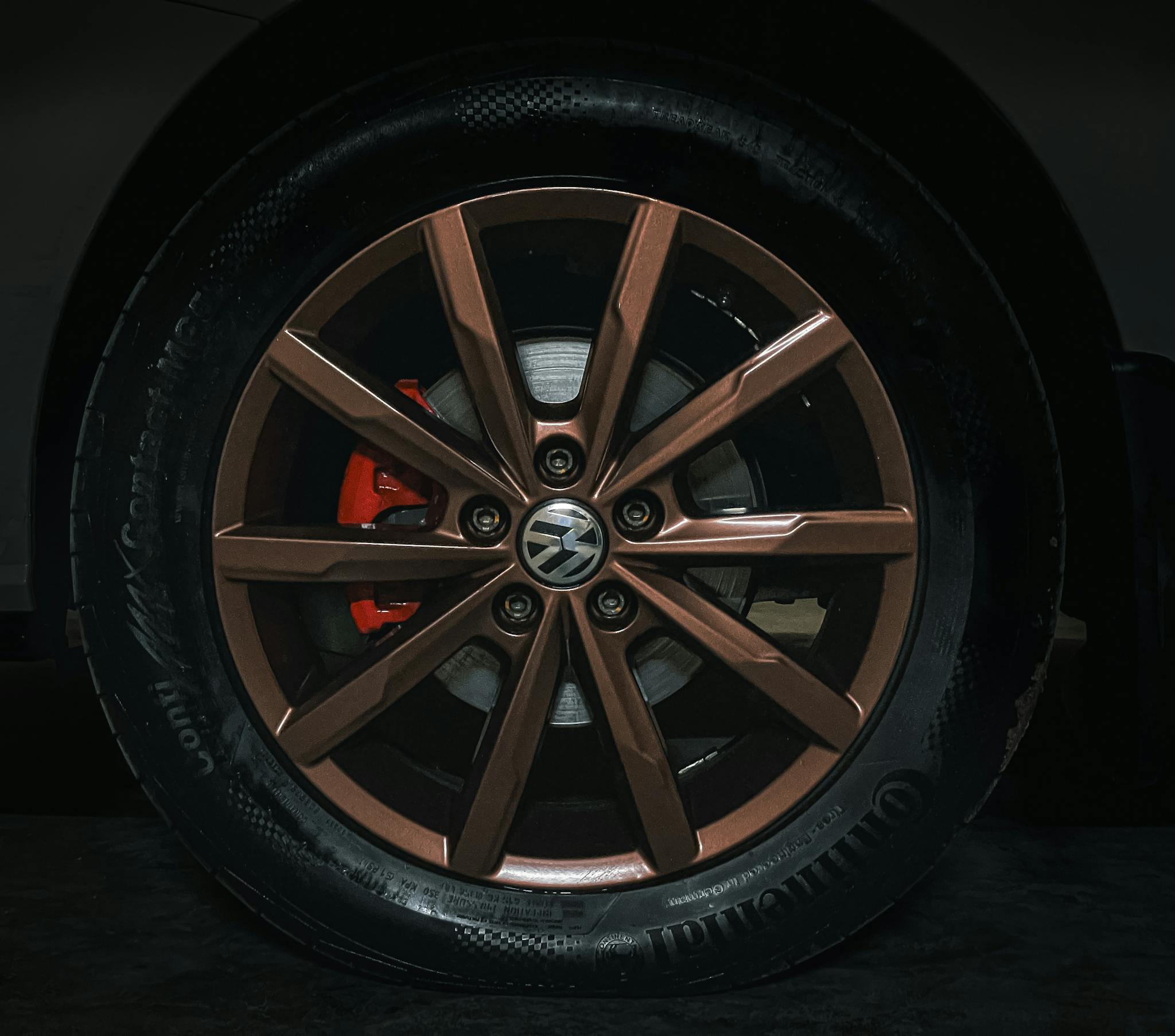 Close-up view of a sleek Volkswagen alloy wheel with a modern design set against a dark backdrop.