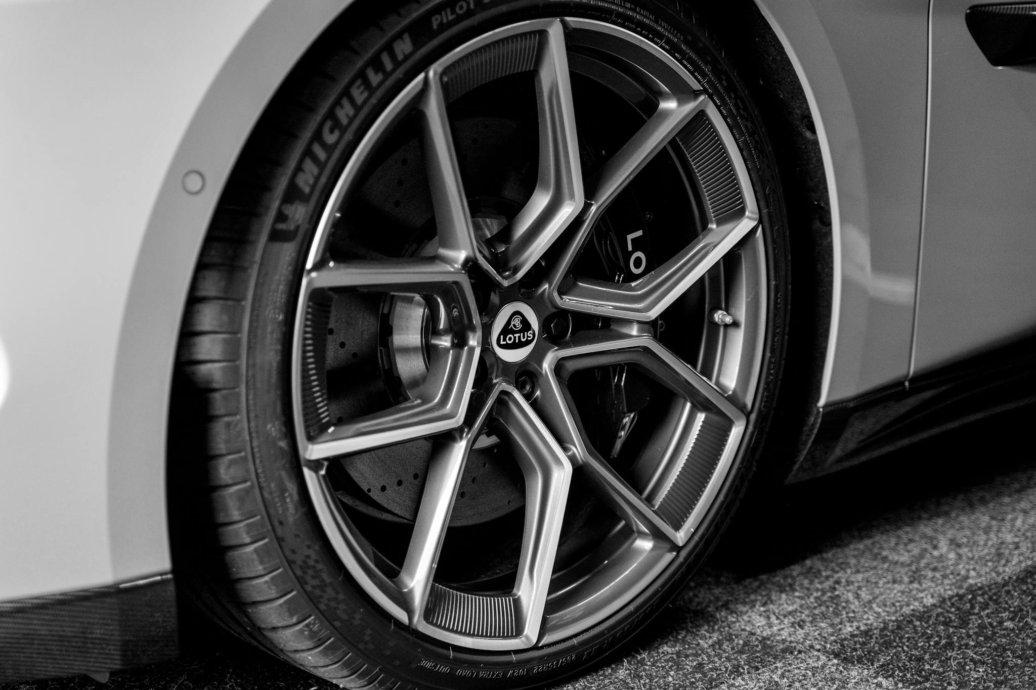 Detailed close-up of a Lotus car wheel showcasing intricate design in black and white.